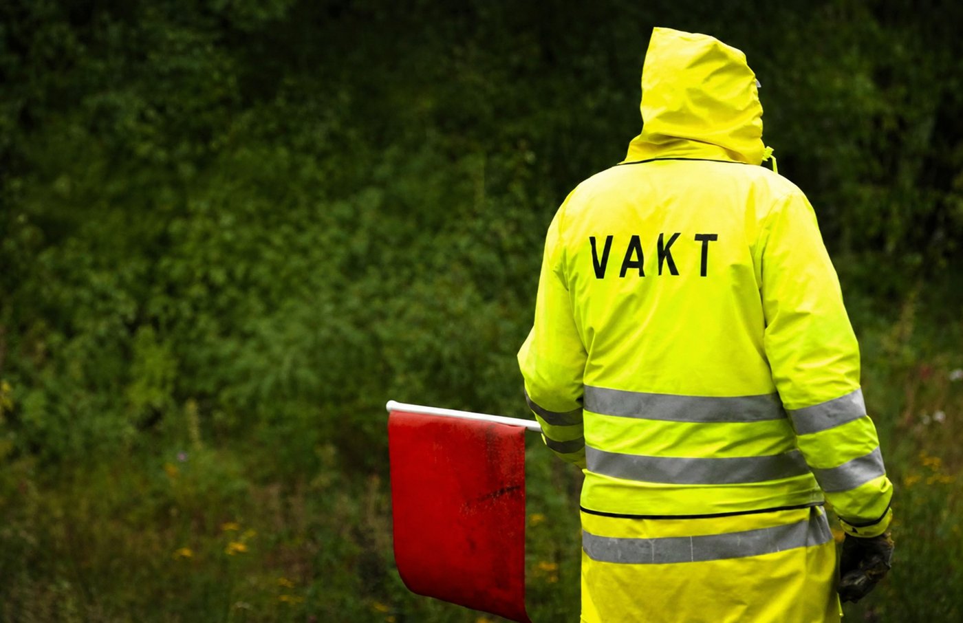 Flaggvakt från Bergholms i varselkläder med flagga vid ett vägarbete i Stockholm